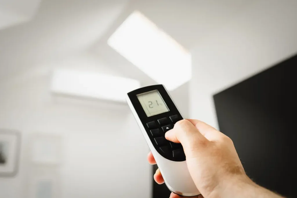 Hand adjusting an air conditioner temperature with a remote control