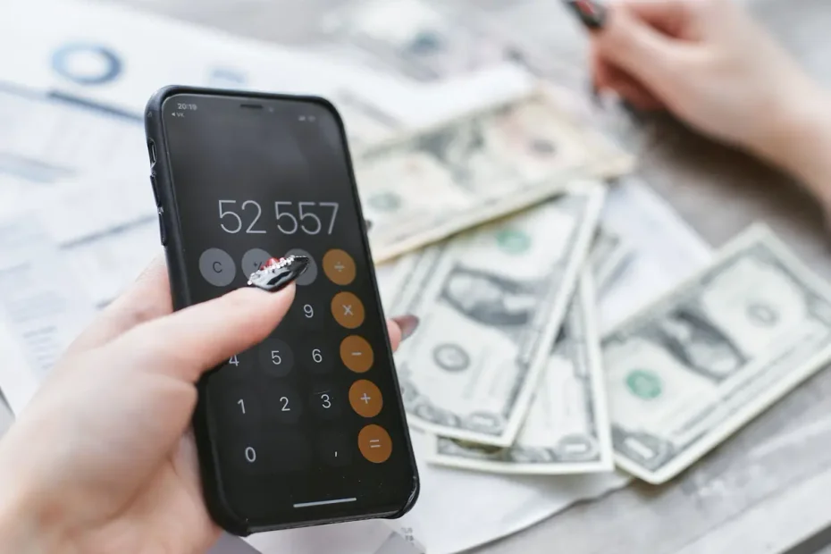 A person reviewing household expenses with a smartphone and utility bills.